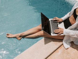 woman sitting on poolside using laptop