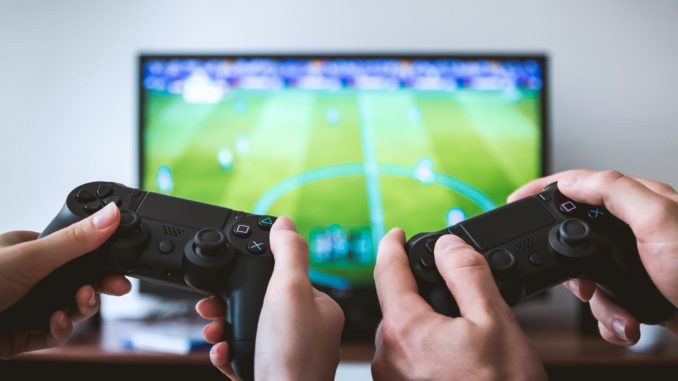 two people holding black gaming consoles